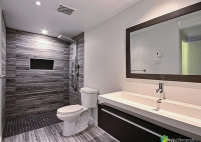 Cette salle de bain au caractère scandinave dégage une ambiance à la fois intense et revigorante. La céramique d’imitation bois apporte le côté spa nature à la pièce. Les couleurs foncées des matériaux et de l’ameublement lui donnent par ailleurs son caractère unique. On y sent déjà les effluves de savon vivifiant!